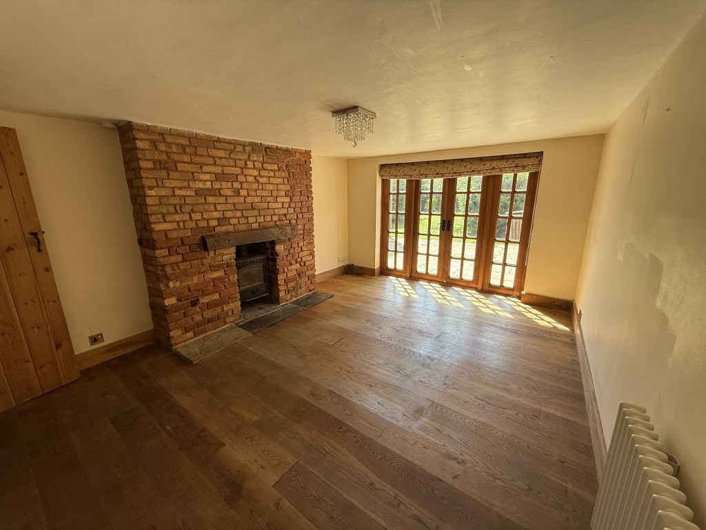 Lot: 168 - DETACHED COTTAGE IN ESSEX VILLAGE LOCATION - Living Room with fireplace and french doors to garden